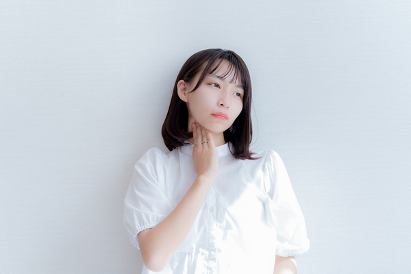 痛みで首を押さえる女性